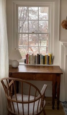 a wooden desk sitting under a window next to a lamp