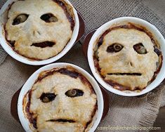 three pies with faces drawn on them are sitting on a tablecloth and one has been made to look like an evil face