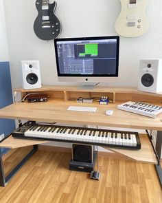 a computer desk with musical instruments and a keyboard on it in front of a monitor