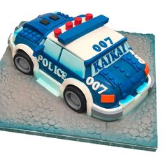 a cake shaped like a police car on top of a sheet covered in frosting