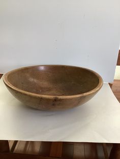 a large wooden bowl sitting on top of a white countertop next to a wall