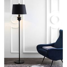 a black floor lamp next to a blue chair in a living room with white walls