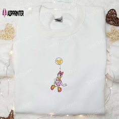 Introducing our enchanting Daisy Duck with Disney Balloon Embroidered Shirt! This delightful piece showcases Daisy Duck holding a bunch of vibrant balloons, adding a touch of whimsy to any outfit. Made with high-quality materials, the shirt is soft, comfortable, and durable, ensuring long-lasting wear. With its intricate embroidery, it brings the beloved Disney character to life, making it a perfect addition to any Disney enthusiast's wardrobe. Whether it's for a casual day out or a special occasion, this shirt is versatile and stylish. Ideal as a gift, it will surely bring joy and smiles to girls of all ages. Grab this adorable Daisy Duck shirt now and let the magic unfold!
Elevate your little one's fashion game with our Disney Cartoon Embroidered Hoodie! Featuring beloved Disney characte Disney Balloon, Disney Balloons, Cartoon Hoodie, Embroidered Apparel, Duck Shirt, Holiday Hoodies, Best Gift Ideas, Daisy Duck, Girl Standing