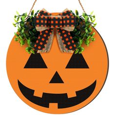 a pumpkin shaped door hanger with a bow on it's head and green leaves