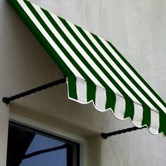 a green and white striped awning hanging from the side of a building next to a window