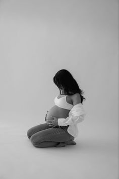 a pregnant woman sitting on the floor with her hands in her stomach