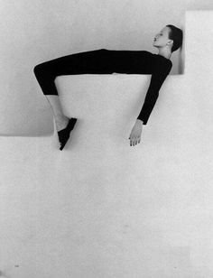 black and white photograph of a woman leaning against a wall with her arms stretched out