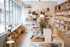 the inside of a book store with many books on shelves and plants in vases