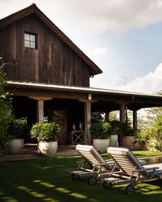 two lawn chairs sitting in front of a wooden building with potted plants on it