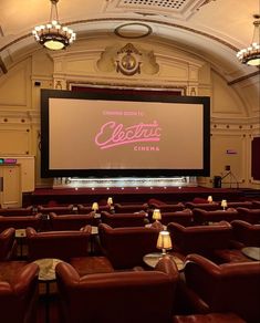 an empty theater with red leather seats and a large screen on the wall that says electric cinema