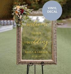 a welcome sign with flowers and greenery on the front is displayed in an ornate frame