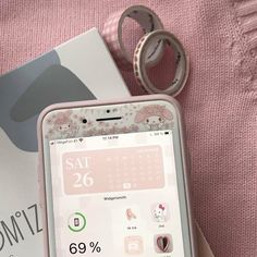 a cell phone sitting on top of a pink blanket next to a box with a ring