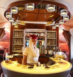 a woman standing in front of a counter with pastries on it, and an airplane bar behind her