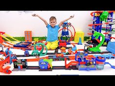 a young boy sitting on top of a train set with his arms in the air