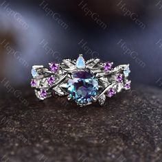 a ring with purple and blue stones on it sitting on top of a stone surface