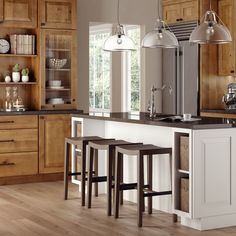 a kitchen with wooden cabinets and white counter tops, two stools in front of the island