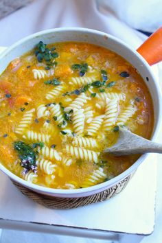 a bowl of pasta soup with carrots and spinach