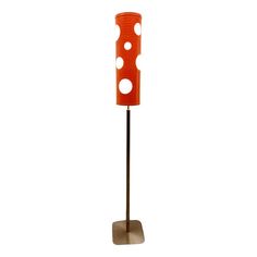 an orange floor lamp with three holes on the top and one hole in the middle