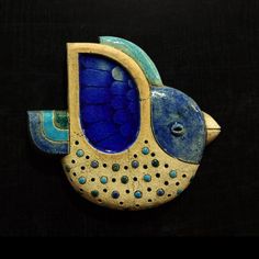 a blue and yellow ceramic bird on a black background