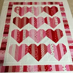 a quilted table runner with several hearts on the top and one in the middle