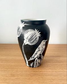 a black and white vase sitting on top of a wooden table