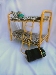 a yellow bunk bed sitting next to a black and white striped bag on top of it