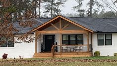 a white house with black shutters on the front porch and wooden steps leading up to it