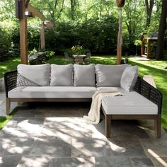 a couch sitting on top of a stone floor next to a wooden pergoline