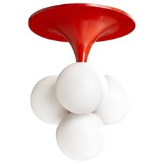 three white balls on top of each other in front of a red object that is upside down