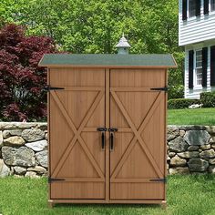 a large wooden storage shed sitting in the middle of a yard next to a stone wall