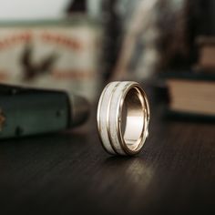 a wedding ring sitting on top of a wooden table next to a stack of books