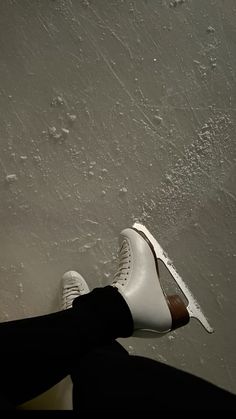 a person wearing white shoes and black pants sitting on the floor with their feet up