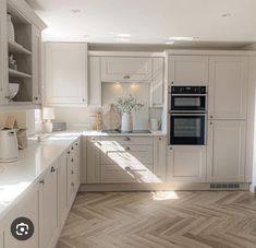 a kitchen with white cabinets and wood flooring