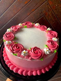 a cake with pink frosting and flowers on the top is sitting on a table