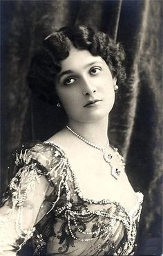 an old black and white photo of a woman in a dress with pearls on it