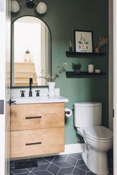 a bathroom with a toilet, sink and mirror on the wall next to a shelf