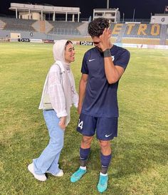 a man and woman standing on top of a soccer field