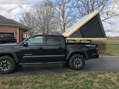 a black truck parked in front of a house with a tarp on the back