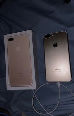 two iphones sitting next to each other on a bed with wires plugged in