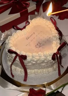 a heart shaped cake sitting on top of a table next to red roses and candles