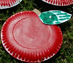 three paper plates with handprints on them sitting in the middle of some grass