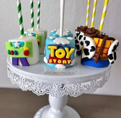 there are four toy story cakes on the cake stand with candles in them and frosting