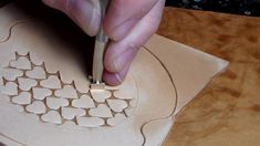 a person using a pair of scissors to cut out shapes on a piece of wood