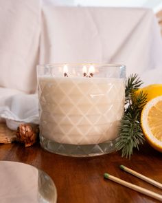 a candle sitting on top of a wooden table next to an orange and pine cone