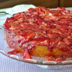 a cake with strawberries on top sitting on a glass plate