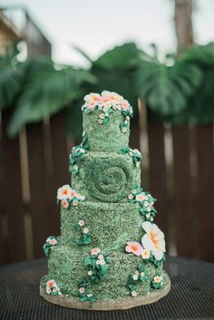 a three tiered green cake with flowers on it