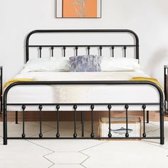 a black metal bed frame with white sheets and pillows