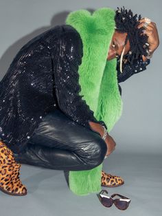 a woman in black and green outfit crouching down with her hands on her head