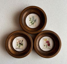 three small wooden bowls with flowers painted on the lids and bottom, sitting on a white surface