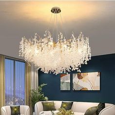 a living room filled with white furniture and a chandelier hanging from the ceiling